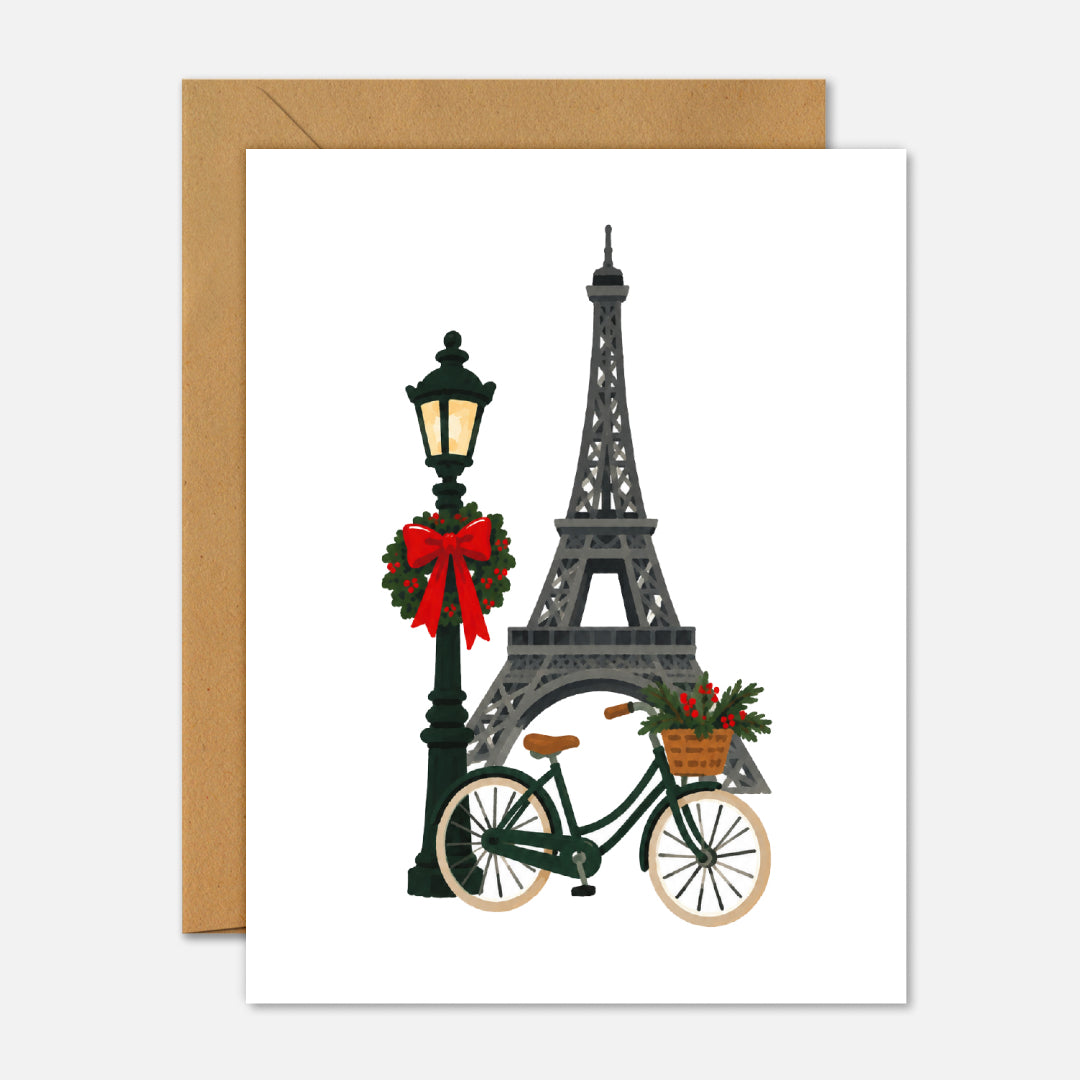 Christmas In Paris greeting card featuring an illustrated festive Parisian city scene with Christmas decorations and French architecture.