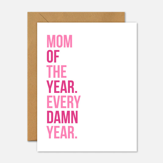 Greeting card with pink text 'Mom of the Year. Every Damn Year.' on a white background with a brown envelope.