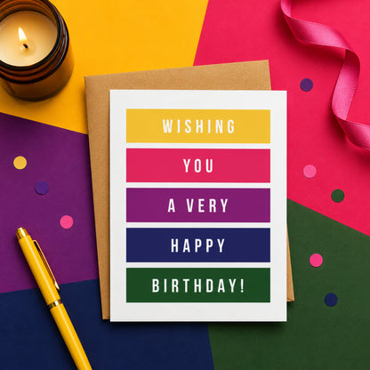 Send cheerful birthday wishes with a colorful modern greeting card featuring bold striped typography, blank inside with a kraft envelope.