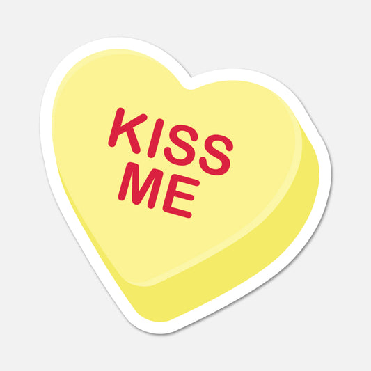 Heart-shaped yellow sticker with 'KISS ME' text on a light gray background