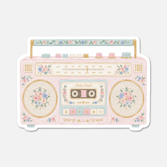 A retro-style cassette radio sticker or decal featuring a pastel pink body with floral details, gold trim, and decorative buttons, shown on a light gray background.