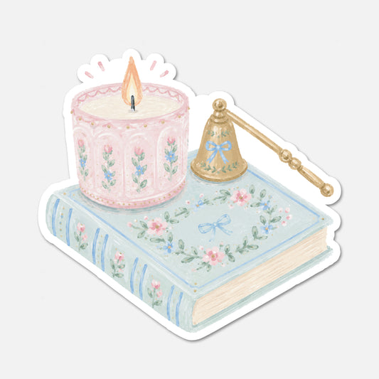 A die-cut sticker featuring a pastel illustration of a pink candle, a light blue floral book, and a gold candle snuffer on a white background.