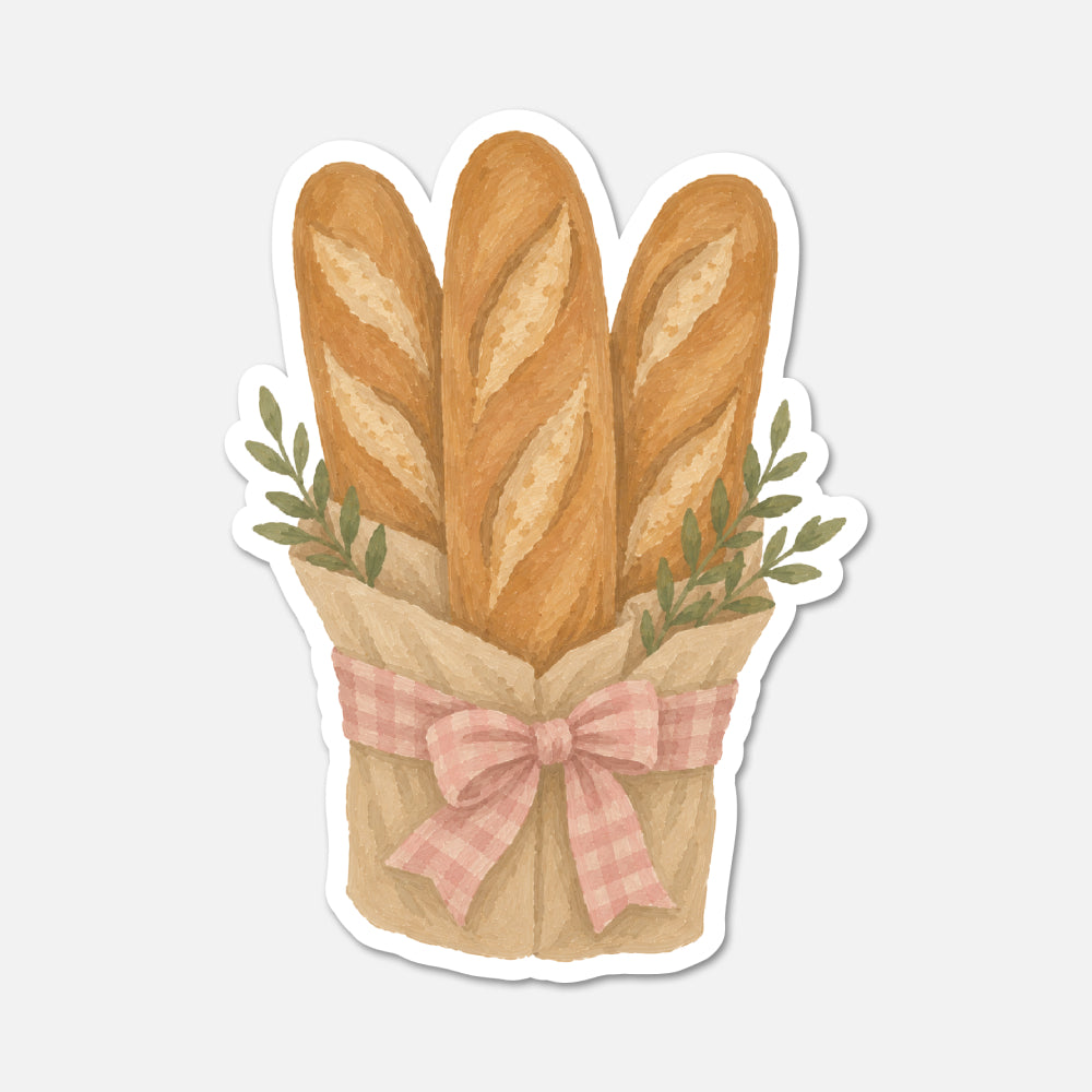 A die-cut sticker featuring an illustration of three baguettes wrapped in brown paper with a pink gingham ribbon and green leaves, shown on a light gray background.