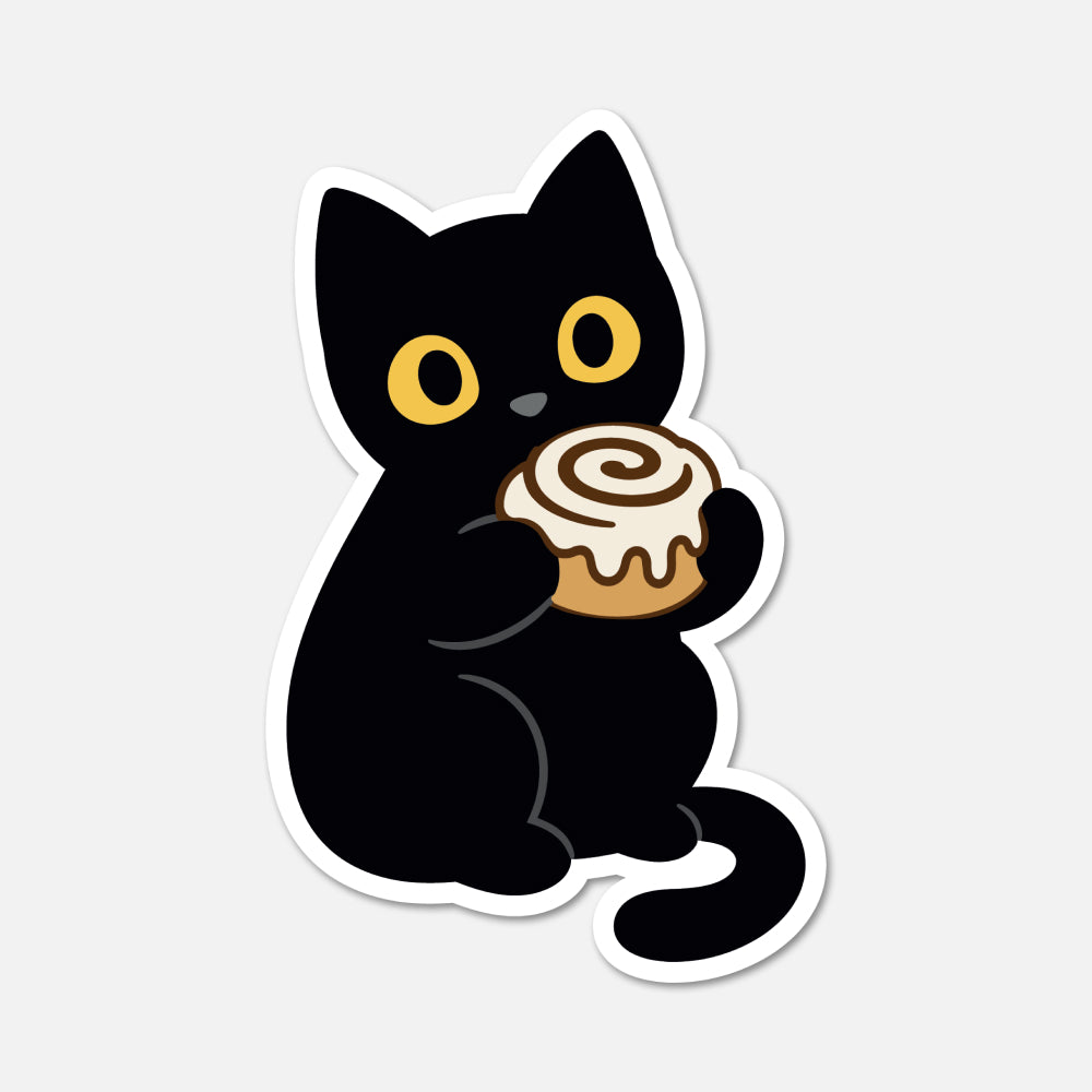 A die-cut sticker featuring a cartoon black cat holding a cinnamon roll, shown on a light gray background.