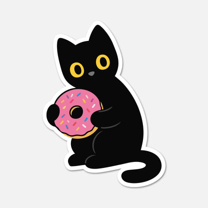 A die-cut sticker featuring a cute cartoon black cat holding a pink frosted donut with colorful sprinkles, shown on a light gray background.