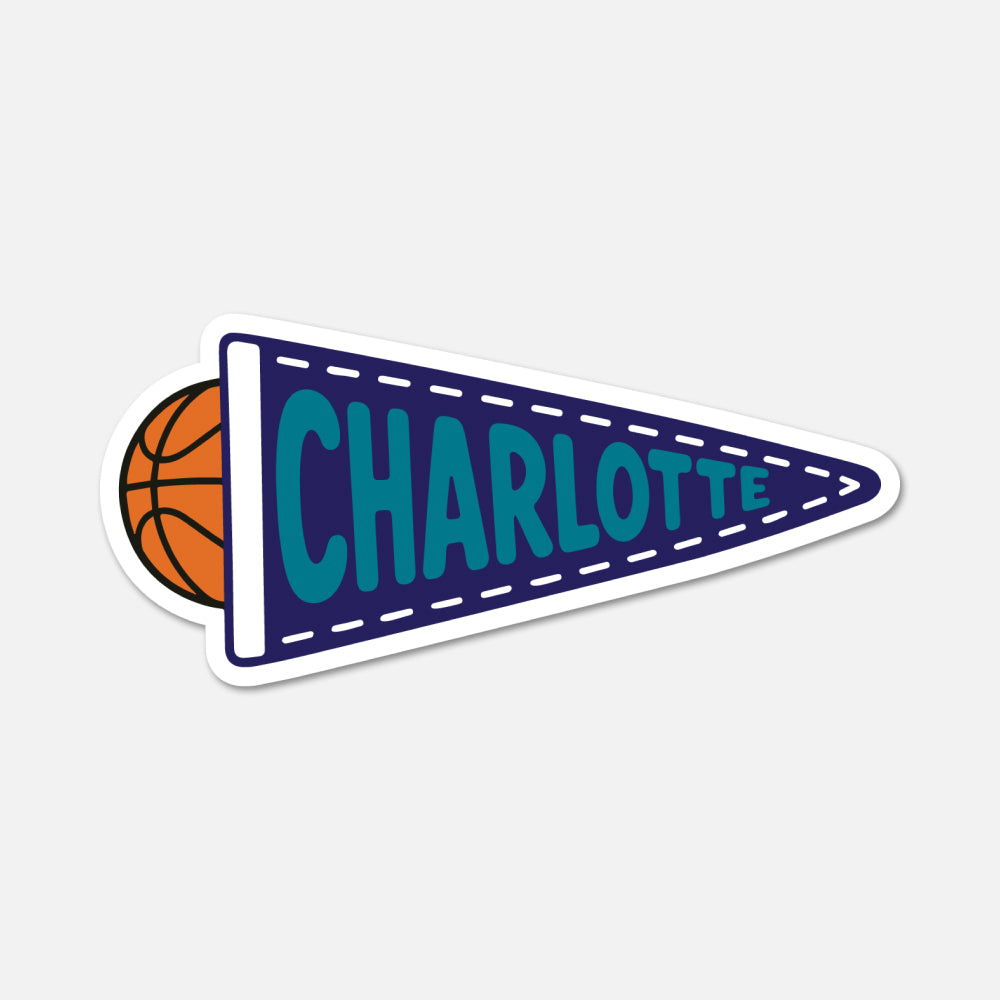 A die-cut sticker featuring a navy blue pennant with the word 'CHARLOTTE' in teal, a white border, and an orange basketball peeking out from behind on the left, shown on a light gray background.