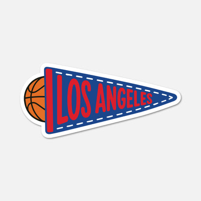 A die-cut sticker of a Los Angeles basketball-themed pennant, featuring a blue pennant with red lettering and a partial basketball peeking out from behind on the left, set against a light gray background.