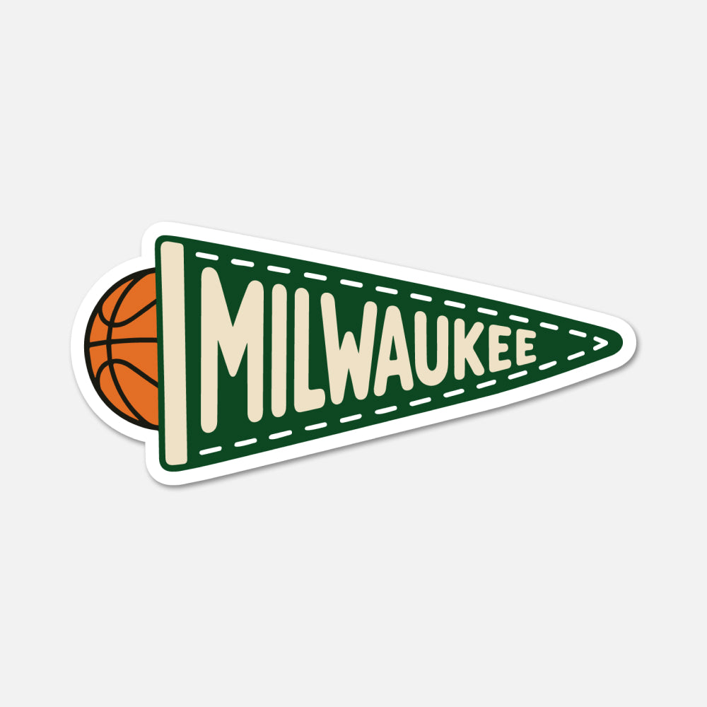 A die-cut sticker featuring a green triangular pennant with the word 'MILWAUKEE' in cream lettering, a basketball peeking out from behind the left edge, and a white border, shown on a light gray background.
