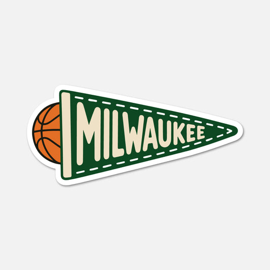A die-cut sticker featuring a green triangular pennant with the word 'MILWAUKEE' in cream lettering, a basketball peeking out from behind the left edge, and a white border, shown on a light gray background.