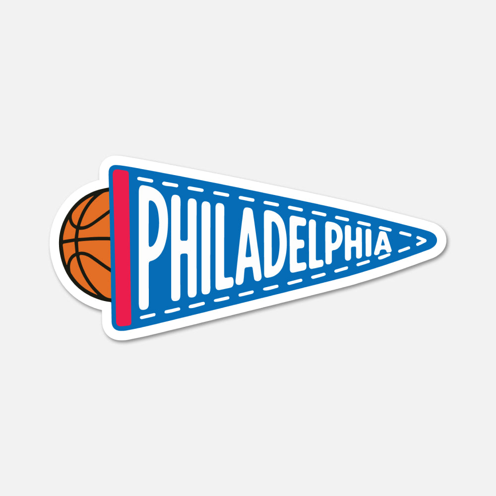 A die-cut sticker of a Philadelphia basketball-themed pennant, featuring a blue pennant with white lettering, a red stripe, and a basketball peeking out from behind on the left, shown on a light gray background.