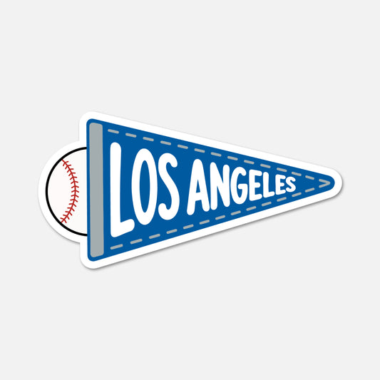 A die-cut sticker shaped like a blue Los Angeles pennant with a baseball peeking out from behind it, shown on a light gray background.