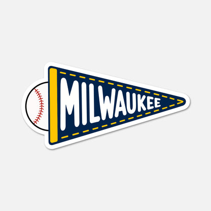A die-cut sticker shaped like a Milwaukee sports pennant, featuring a navy blue pennant with yellow trim, white 'MILWAUKEE' lettering, a yellow vertical stripe, and a baseball peeking out from behind on the left, shown on a light gray background.
