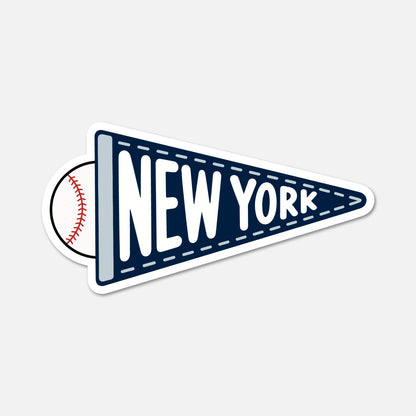 A die-cut sticker shaped like a navy blue pennant with white dashed stitching, the words "NEW YORK" in large white letters, and a baseball peeking out from behind on the left, shown on a light gray background.