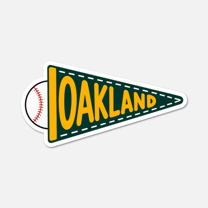 A die-cut sticker shaped like a green and yellow Oakland pennant, with a baseball peeking out from behind the left side. The word 'OAKLAND' is printed in large yellow letters across the pennant, and the sticker is shown on a light gray background.