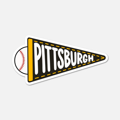 A die-cut sticker shaped like a black and yellow Pittsburgh pennant, with a baseball partially visible behind it on the left. The word 'PITTSBURGH' is printed across the pennant in large white letters with a black outline.