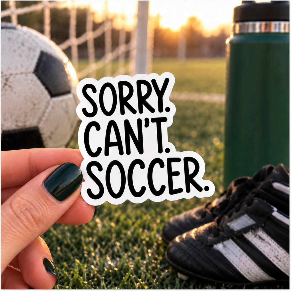 A hand with dark green nail polish holds a die-cut sticker that reads 'SORRY. CAN'T. SOCCER.'