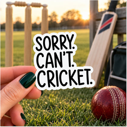 A hand with dark green nail polish holds a die-cut sticker that reads 'SORRY. CAN'T. CRICKET.'