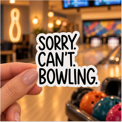 A hand holds a die-cut sticker with the text 'SORRY. CAN'T. BOWLING.'