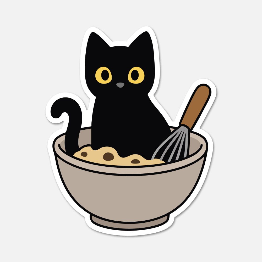 A die-cut sticker featuring a cartoon black cat sitting in a beige bowl with yellow dough and a whisk, shown on a light gray background.